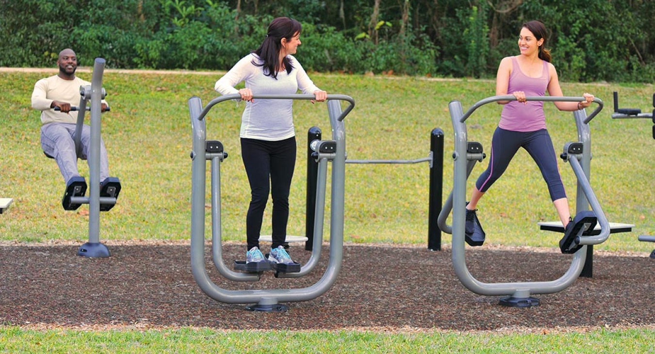 group doing leg exercises on park exercise equipment