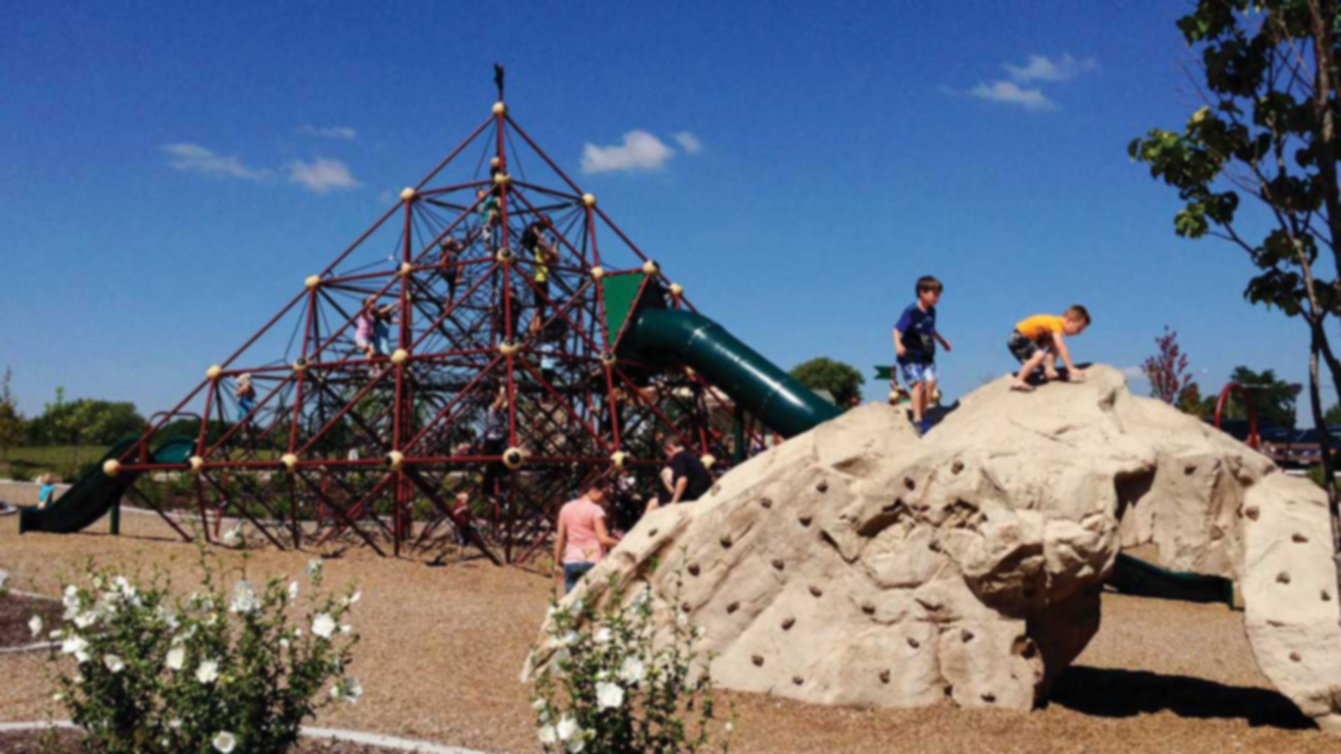 kids climbing on a rock sculpture and rope playground 