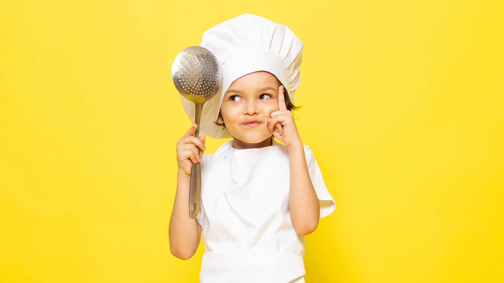 young boy wearing a chef's hat thinking about what to cook