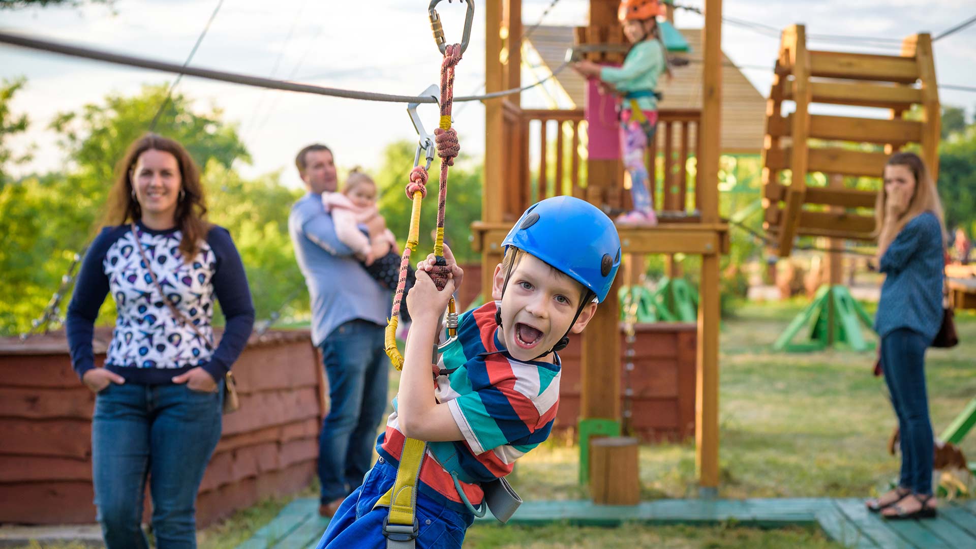 Boy gliding on a rope course with parents watching