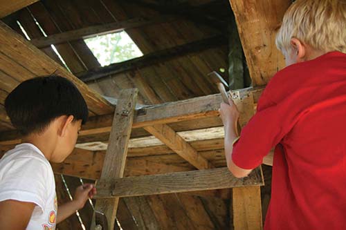 boys hammering nails into a makeshift fort boys hammering nails into a makeshift fort