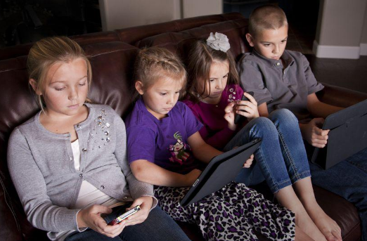 Children on couch playing with digital devices Children on couch playing with digital devices