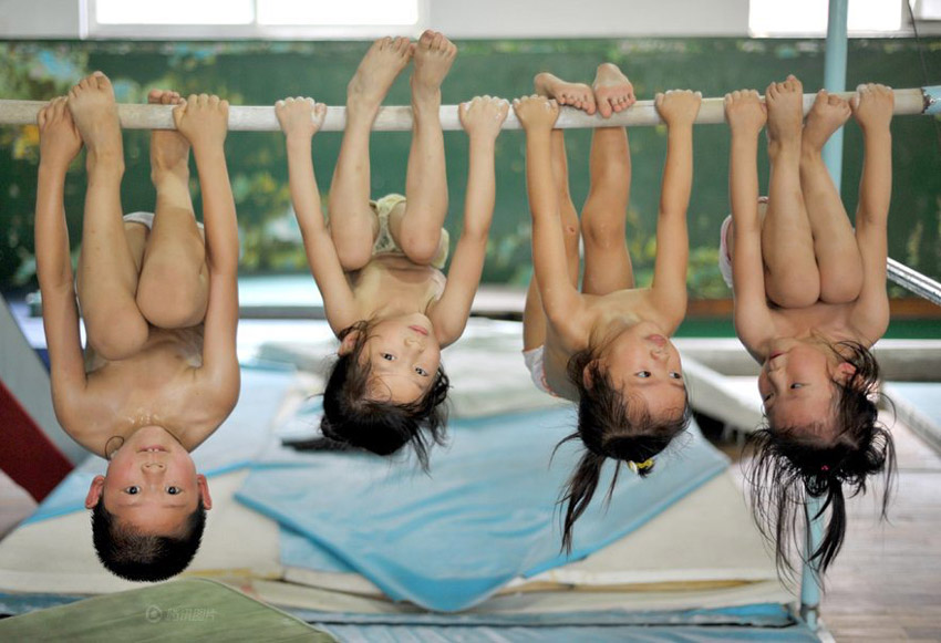 Toddlers hanging upside down from a bar