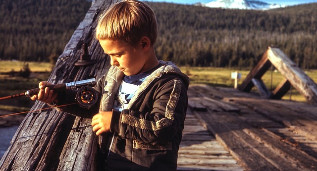 Boy fishing on a wooden bridge