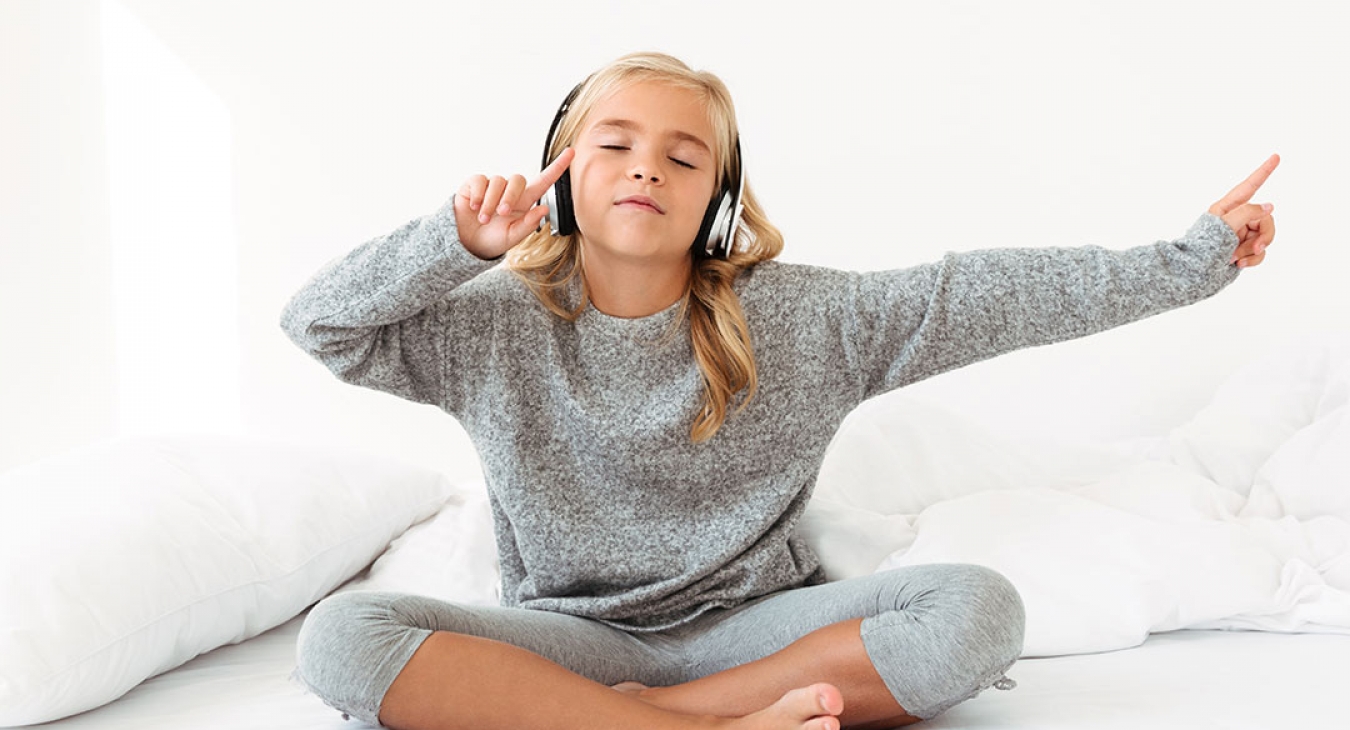 cute little blonde girl listening to music in her bed