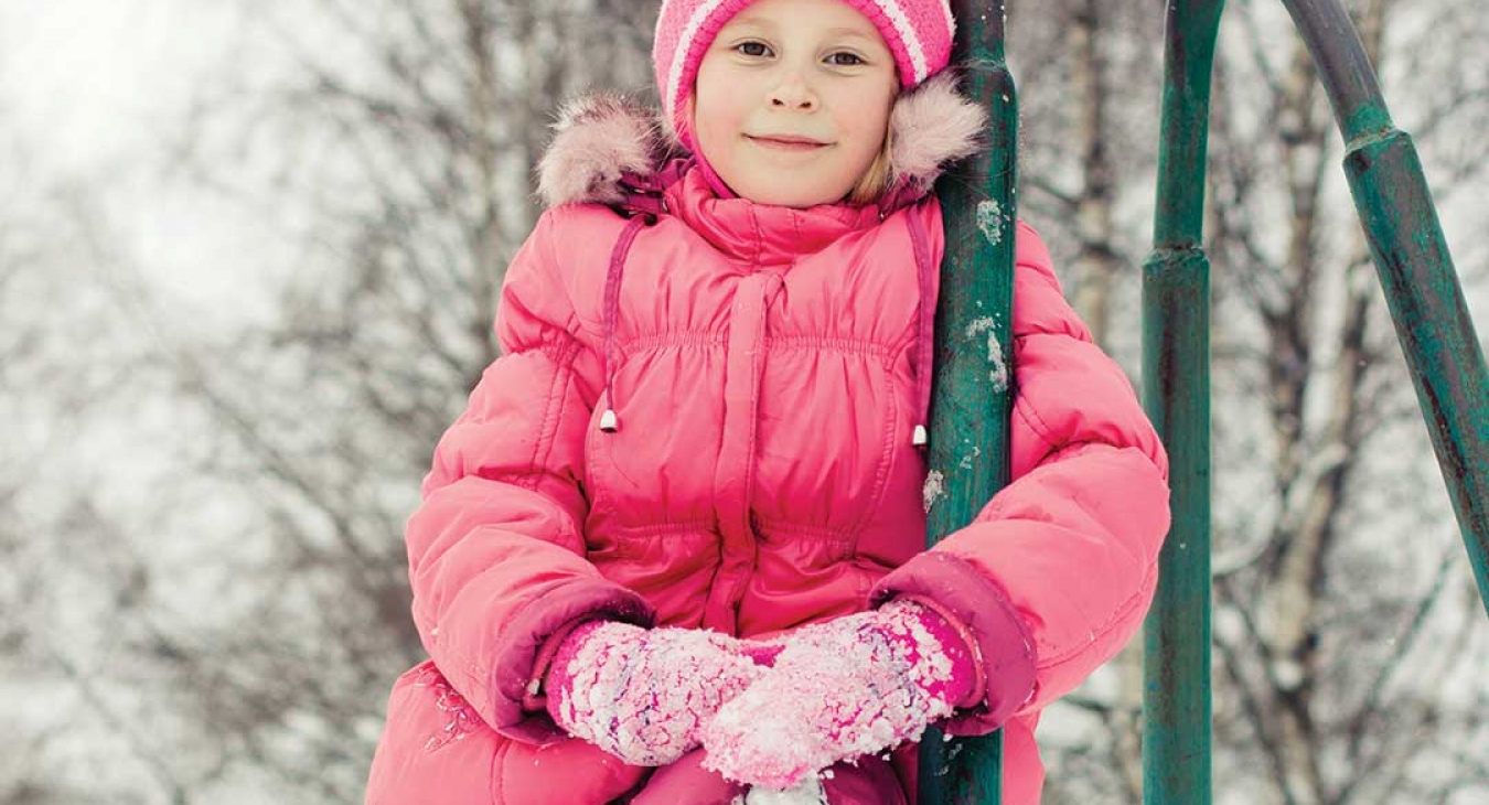 girl in snow clothes climbing on vintage playground