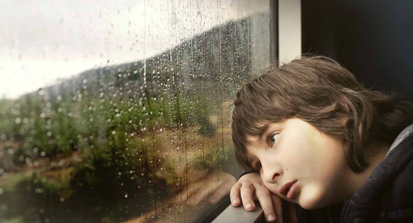 Child with ADHD looking outside on a rainy day