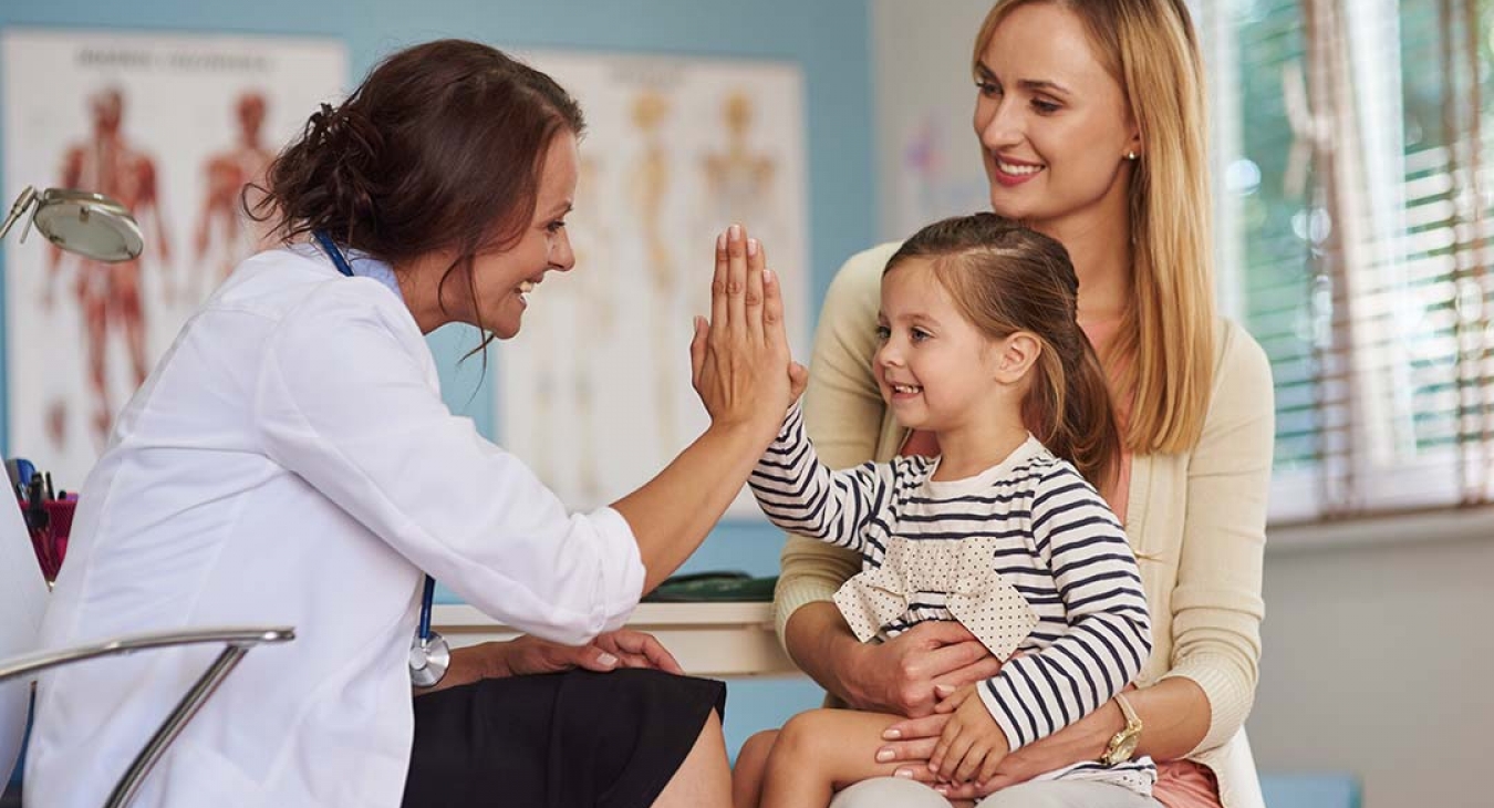 Doctor giving little girl 5 while she sits on her mothers lap