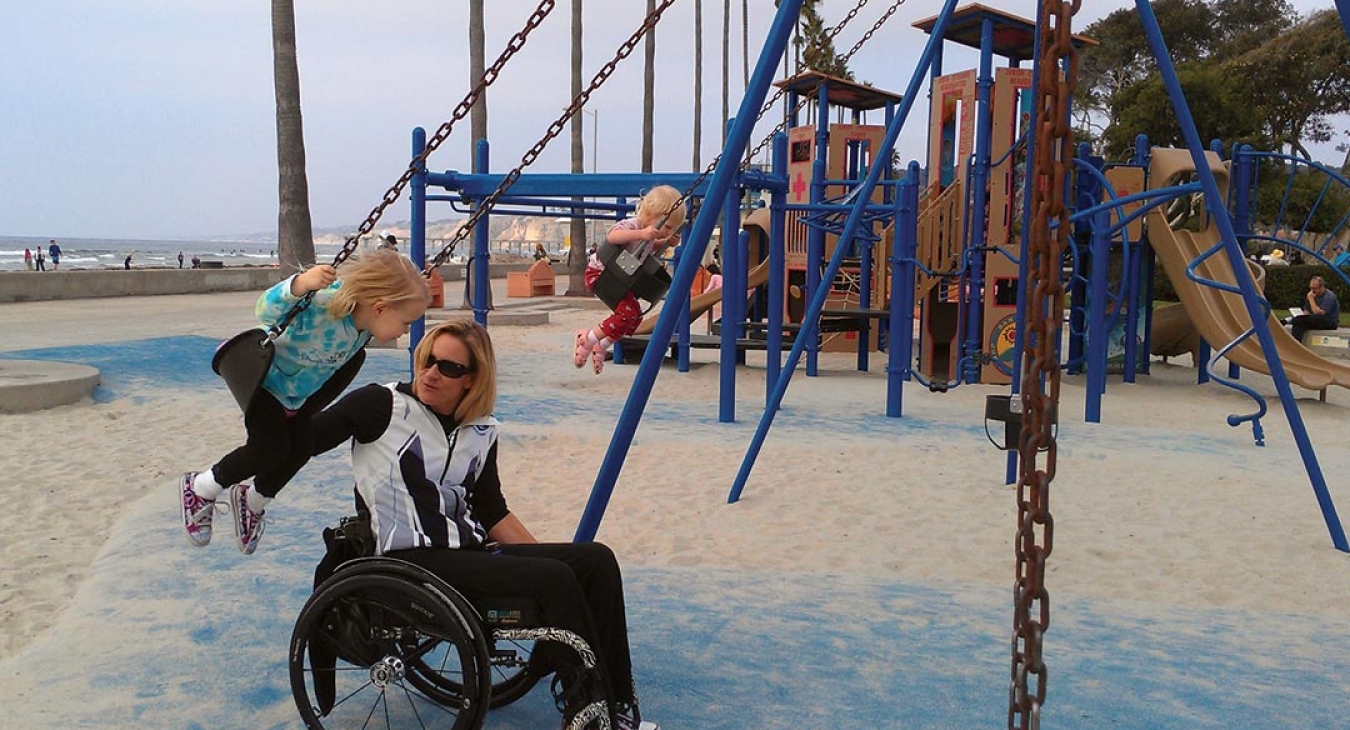 Gold medalist Paralympian, Muffy Davis pushes her daughter on the swings
