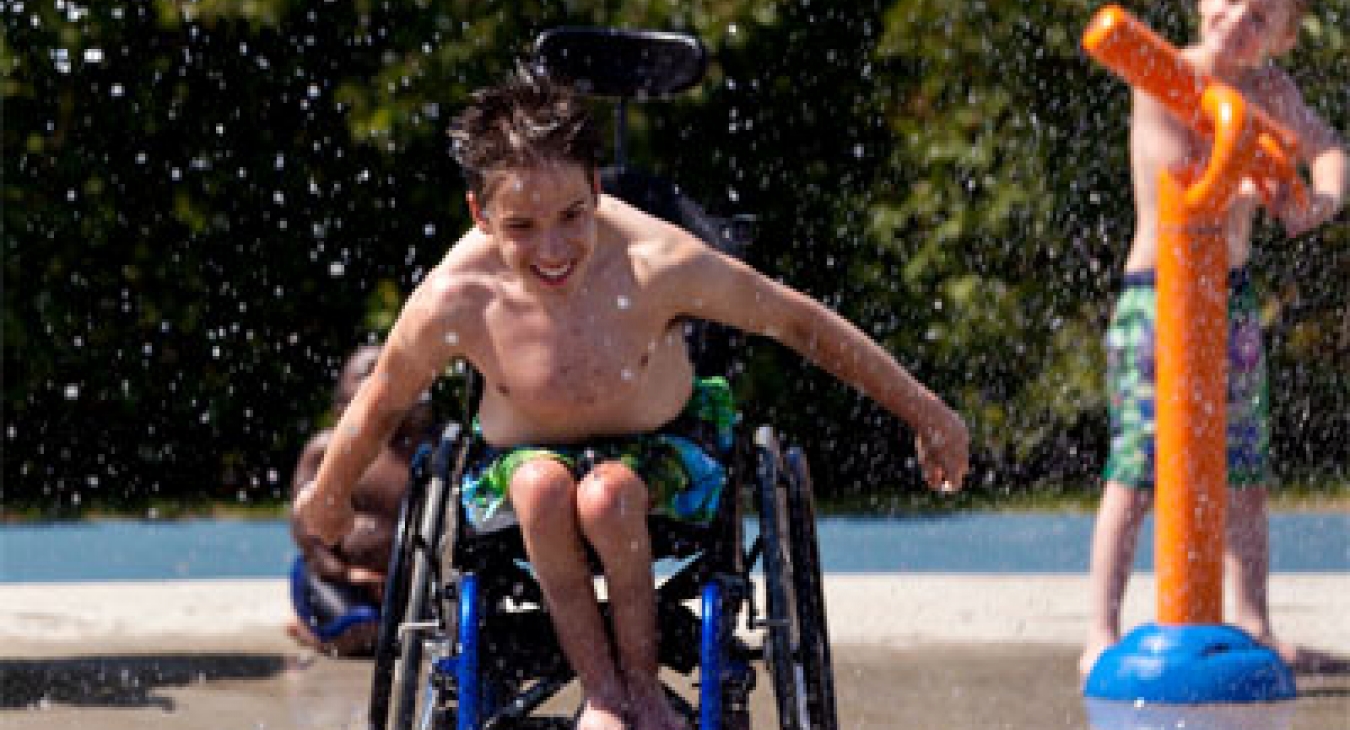 Boy in wheelchair enjoys a splash pad.