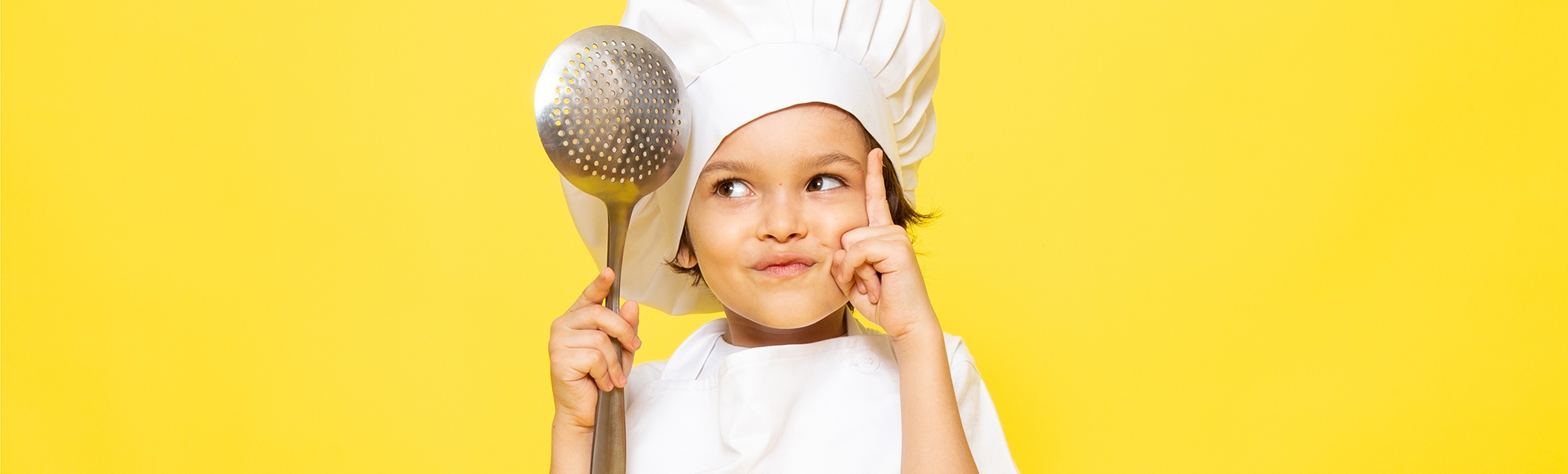 young boy wearing a chef's hat thinking about what to cook