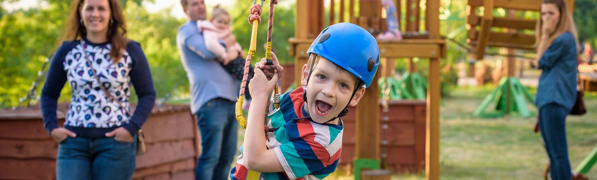Boy gliding on a rope course with parents watching