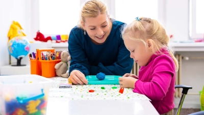 Therapist using games and play to help little blonde girl