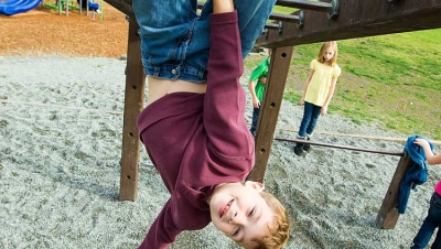 Child hanging from monkey bars.